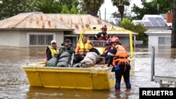 FILE - State Emergency Service (SES) personnel navigate floodwaters with residents and supplies aboard a watercraft at the town of Forbes, in the Central West region of New South Wales, Australia, November 16, 2022. 