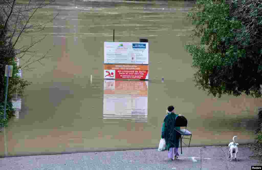 Emily Jean Pierre and her dog Vixen walk near the Russian River where it flooded Johnson’s beach in Guerneville, California.