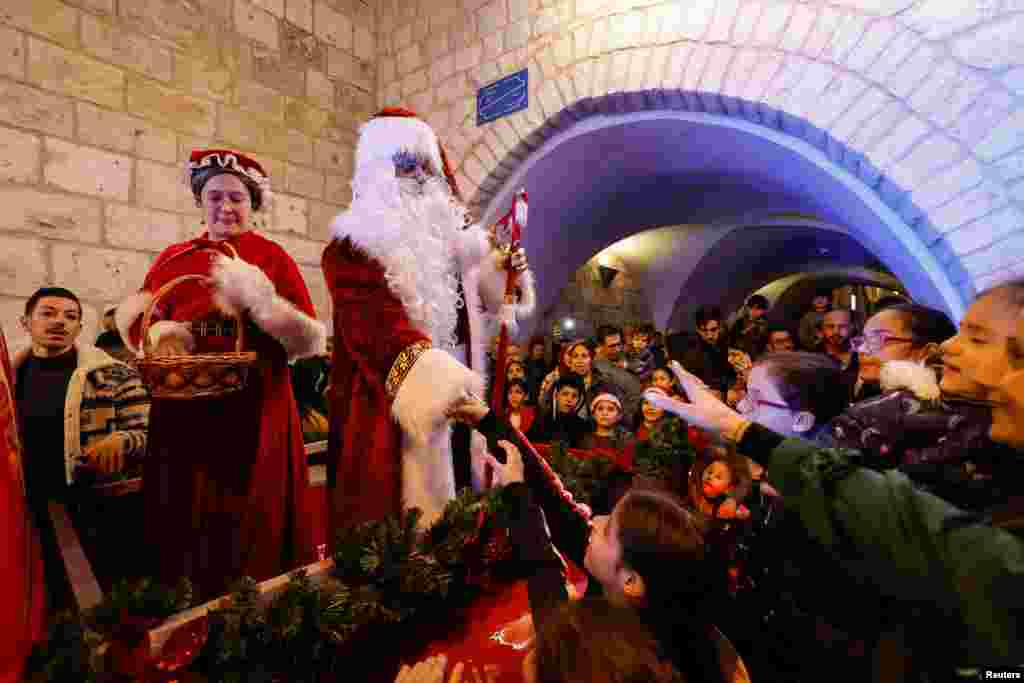 A Palestinian dressed as Santa Claus shakes hands with children during a celebration in Bethlehem, in the Israeli-occupied West Bank, Dec. 4, 2022.