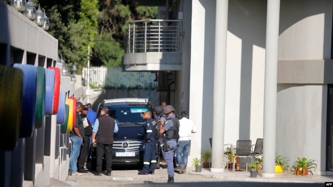 FILE - In this file photo taken on Feb. 14, 2018 a police van and uniformed and plainclothes police officers are seen inside the compound of the controversial business family Gupta in Johannesburg. 