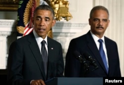 FILE - President Barack Obama, accompanied by Attorney General Eric Holder, speaks in the State Dining Room of the White House, Sept. 25, 2014.