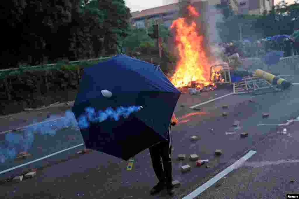 An anti-government protester takes cover under an umbrella during a demonstration in Sha Tin district, on China's National Day in Hong Kong, China.