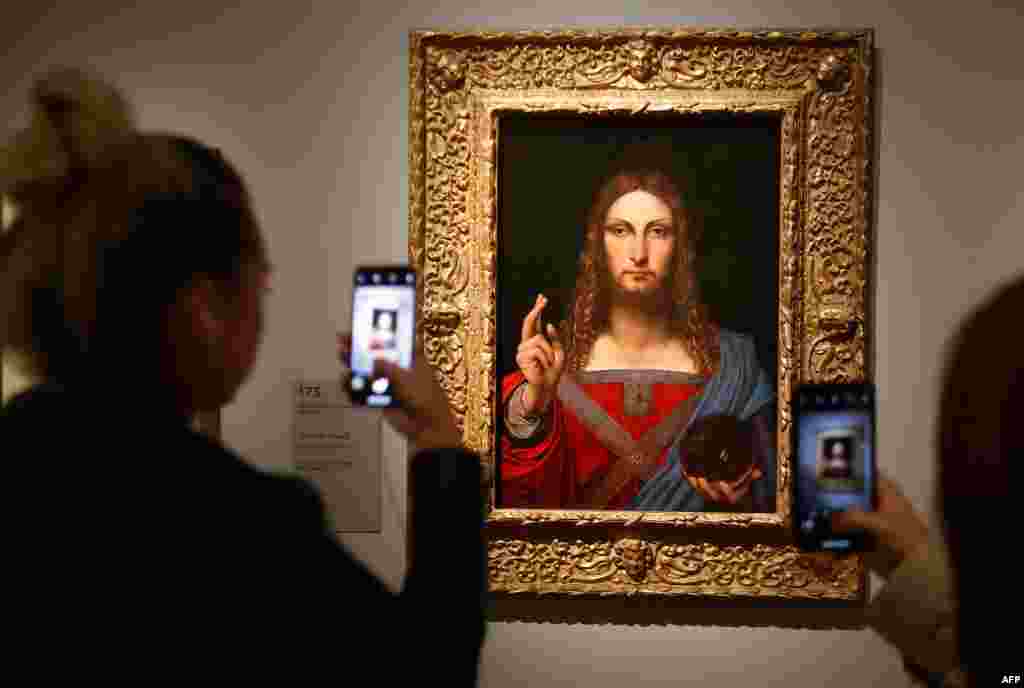 People take pictures of an oil painting by Leonardo da Vinci's " Salvator Mundi" during the opening of the exhibition " Leonardo da Vinci " at the Louvre museum in Paris, France.
