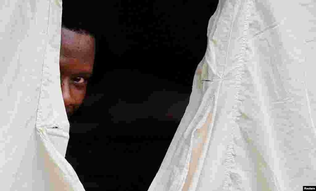 A Haitian refugee peeks out of the window of a tent set up by Canadian Armed Forces near the border in Lacolle, Quebec, Aug. 10, 2017.