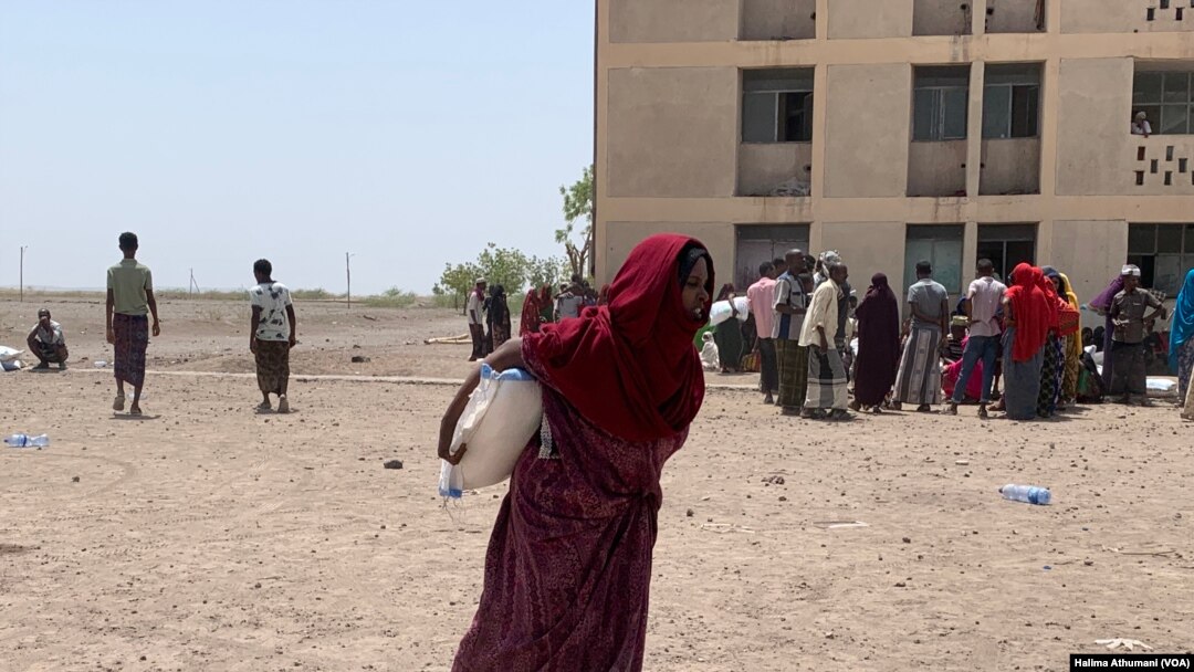 A displaced woman walks away with a food bag at the Dubti displaced peoples site in Northern Ethiopia. (Halima Athumani/VOA)