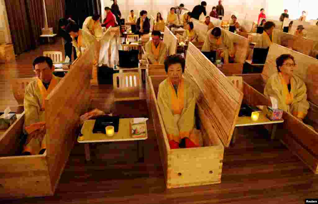 Participants sit inside coffins during a "living funeral" event as part of a "dying well" program in Seoul, South Korea.