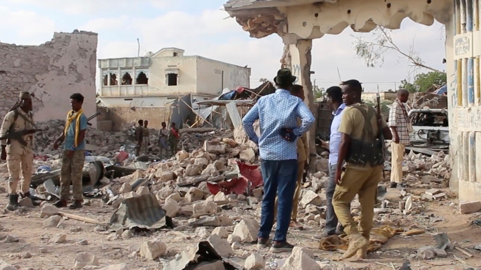 In this image taken from video on March 12, 2025, observers and security officers look over the aftermath of a car bomb explosion the previous day at a hotel in the central Somali city of Beledweyne.