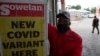 A petrol attendant stands next to a newspaper headline in Pretoria, South Africa, Nov. 27, 2021. 