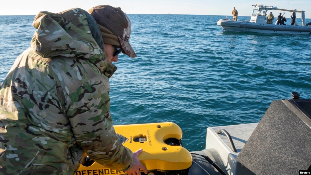 A U.S. Navy sailor conducts a search for debris of a high-altitude Chinese balloon shot down by the U.S. Air Force off the coast of South Carolina on Feb. 7, 2023. 3 more objects, downed the next week over the U.S. and Canada, remain unrecovered.