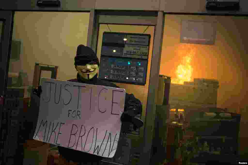 Um manifestante segura um cartaz dizendo "Justiça para Michael Brown", à porta de uma loja da cadeia de supermercados Walgreens, depois do grande júri ter anunciado a decisão de não acusar o polícia que atirou contra Micheal Brown, Ferguson, Missouri, Nov. 24, 2014.
