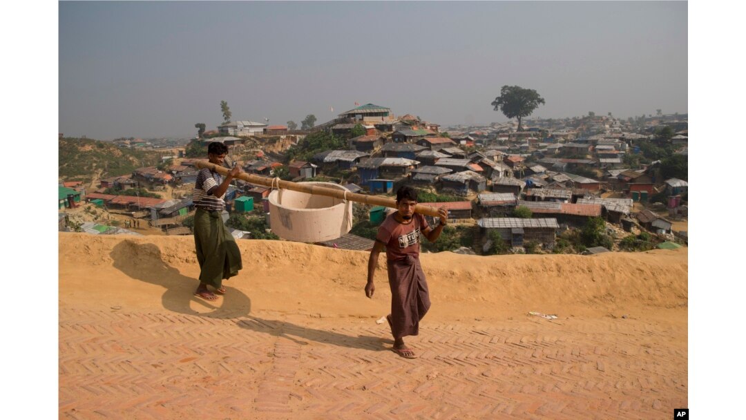 Rohingya refugees carry a hume pipe in Balukhali refugee camp near Cox's Bazar, in Bangladesh, Nov. 17, 2018.