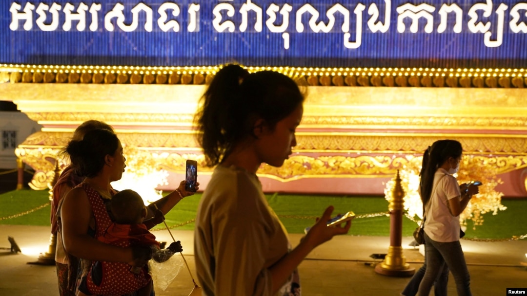 FILE - People walk using their mobiles phones in Phnom Penh, Cambodia, Feb. 18, 2021. The Cambodian government issued a sub-decree to establish a National Internet Gateway that would give it control over the flow of information on the internet.