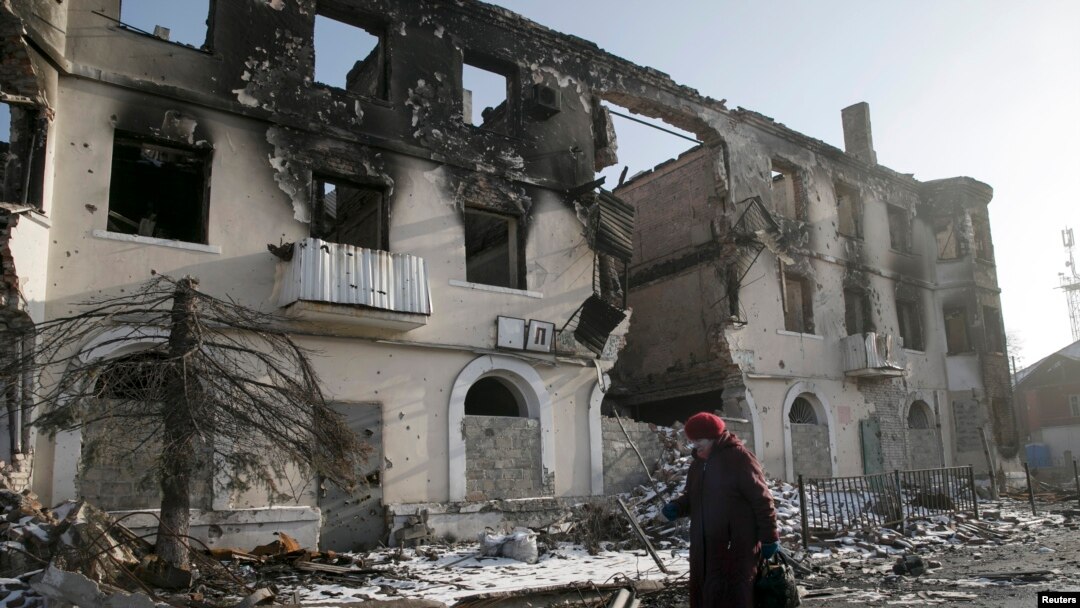 Wata mace take wucewa kusa da wani gini da aka lalata a garin Vuhlehirsk kusa da Donetsk, Ukraine.
