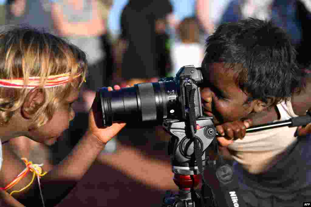 Indigenous Anangu children play with a camera during a ceremony marking the permanent ban on climbing Uluru, also known as Ayers Rock, at Uluru-Kata Tjuta National Park in Australia's Northern Territory.