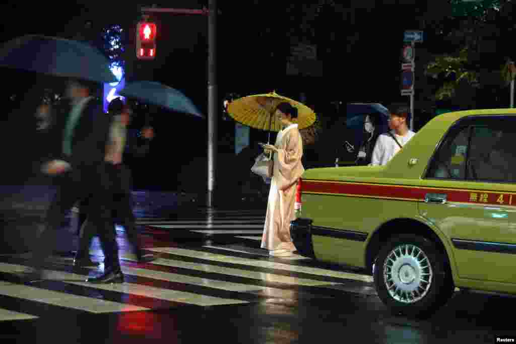 A woman wearing a kimono crosses a street in Tokyo, Japan.