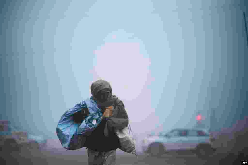 A man crosses a street under heavy foggy conditions in New Delhi, India.