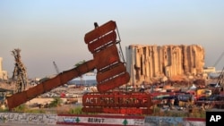 A justice symbol monument is seen in front of towering grain silos that were gutted in the massive Aug. 2020 explosion at the port that claimed the lives of more than 200 people, in Beirut, Lebanon, Aug. 4, 2021. 