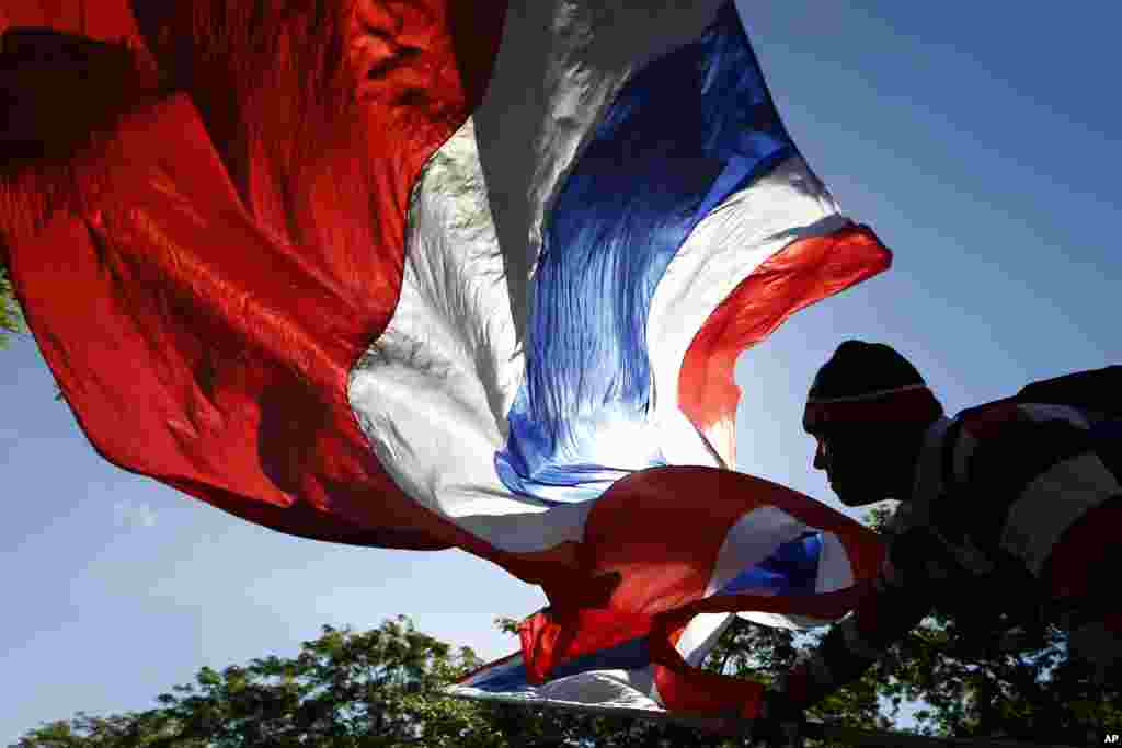 An anti-government protester waves a Thai national flag during a rally in downtown Bangkok. Country's anti-graft commission indicted ousted PM Yingluck Shinawatra on Thursday on charges of dereliction of duty in overseeing a widely criticized rice subsidy program.