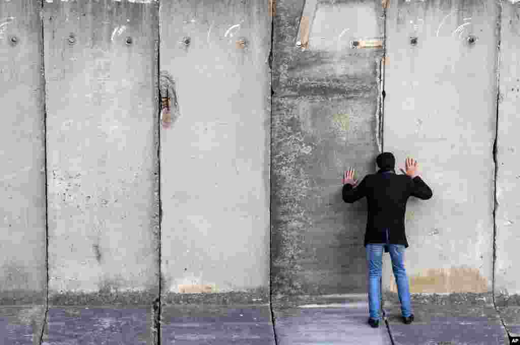 A man looks through a gap during the art performance "Wall watching — climb the wall together" of the National Theatre Weimar prior the 30th anniversary of the falling of the Berlin Wall in Weimar, Germany.