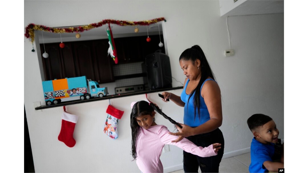 FILE - Diomaris Barboza braids her daughter's hair in the home the family moved into in October 2023, five years after fleeing Venezuela for Colombia, in Lehigh Acres, Fla., Dec. 27, 2023.