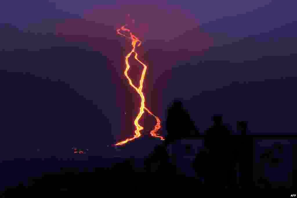 People look at lava erupting from the Piton de la Fournaise or the Peak of the Furnace flowing down the east-south-east face on the Indian Ocean island of Reunion, Aug. 13, 2019.