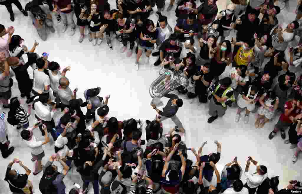 A man holds up a tuba as protesters shout slogans and sing Hong Kong's anthem during a protest at New Town Plaza shopping mall in Hong Kong, China.
