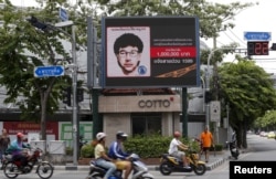FILE - People ride their motorcycles past a digital billboard showing a sketch of the main suspect in Monday's attack on Erawan shrine, in Bangkok, Thailand, August 23, 2015.