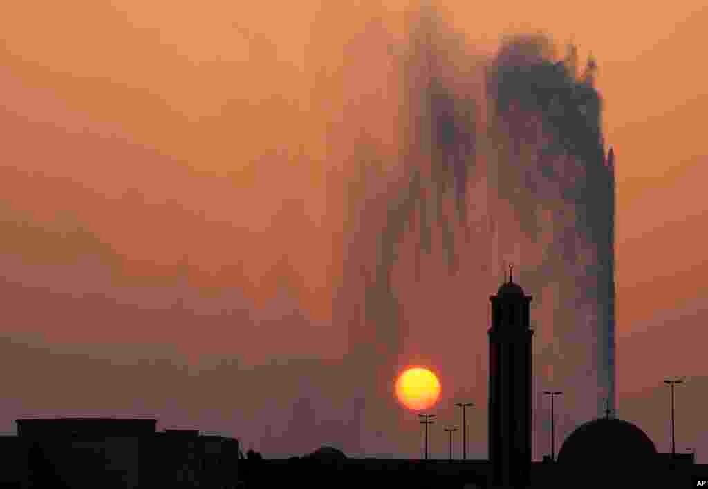 The sun sets behind a mosque and the landmark Jiddah fountain, in Jiddah, Saudi Arabia, Aug. 29, 2019.