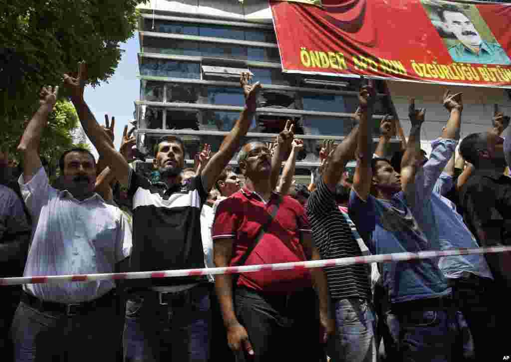 Mourners flash the V-sign as they gather at the site of Monday's explosion in the Turkish town of Suruc near the Syrian border, July 21, 2015.
