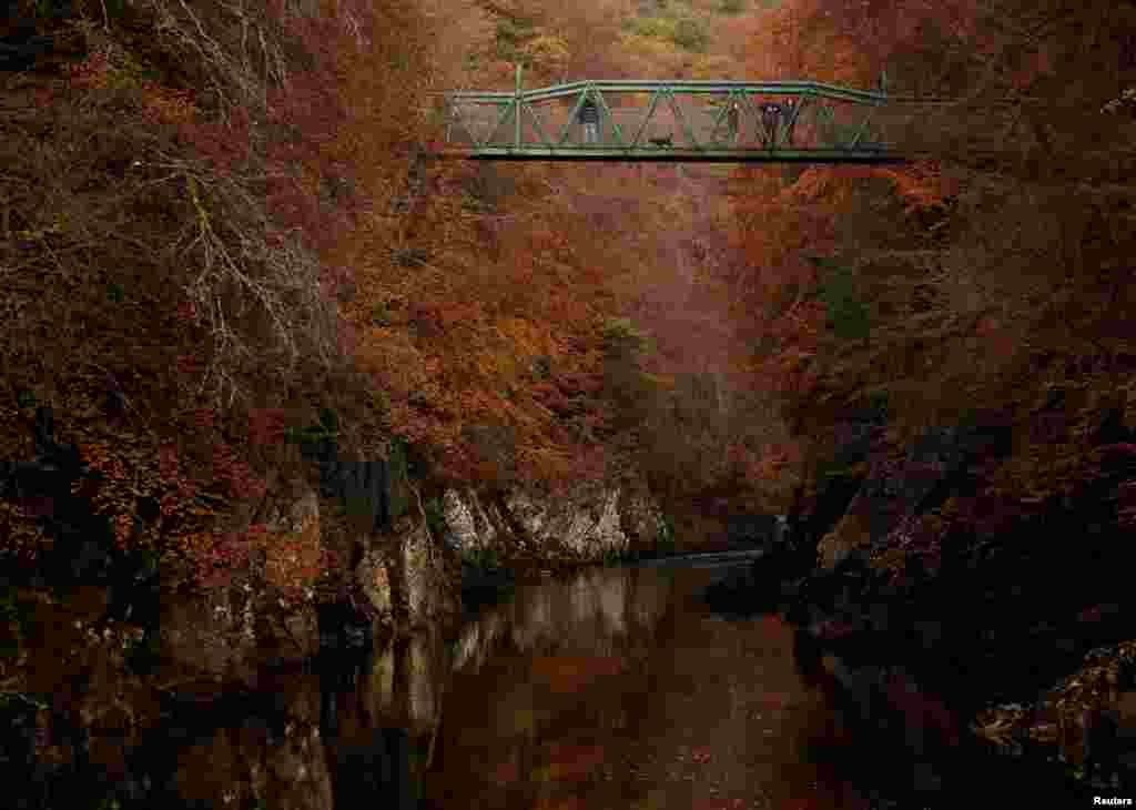 People walk on the bridge over the river Garry, Pitlochry, Scotland, Britain, Oct. 26, 2019.