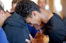 FILE - Austin Burden, 17, cries on the shoulder of a friend after a vigil at the Parkland Baptist Church, for the victims of the shooting at Marjory Stoneman Douglas High School, in Parkland, Fla., Feb. 15, 2018.