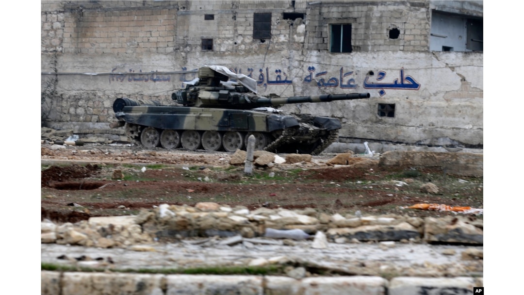 A Syrian army tank is seen in front of a wall with Arabic that reads "Aleppo is the capital of culture" in the east Aleppo neighborhood of Tariq al-Bab, Syria, Dec. 3, 2016.