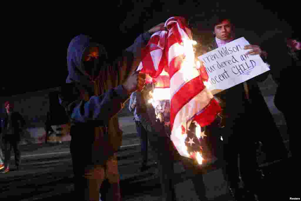 Um manifestante queima uma bandeira dos Estado Unidos, depois de um Grande Júri ter decidido não acusar o agente da polícia Darren Wilson na morte de Michael Brown. Ferguson, Missouri, Nov 24, 2014