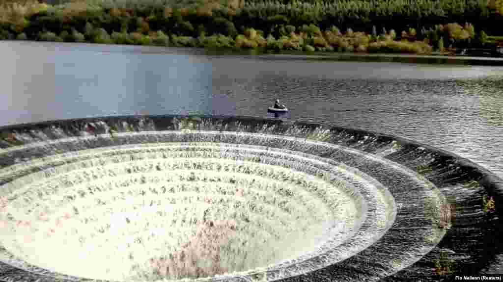 A fisherman floats in a boat close to a 'plughole' on a reservoir in Derbyshire, Britain, in this still image taken from video obtained from social media.