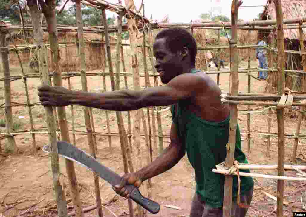 Refugiado angolano constroi um abrigo no acampamento de Caxito, onde 14 mil pessoas se refugiam da sangrenta guerra civil em Angola. Foto de 1998. 