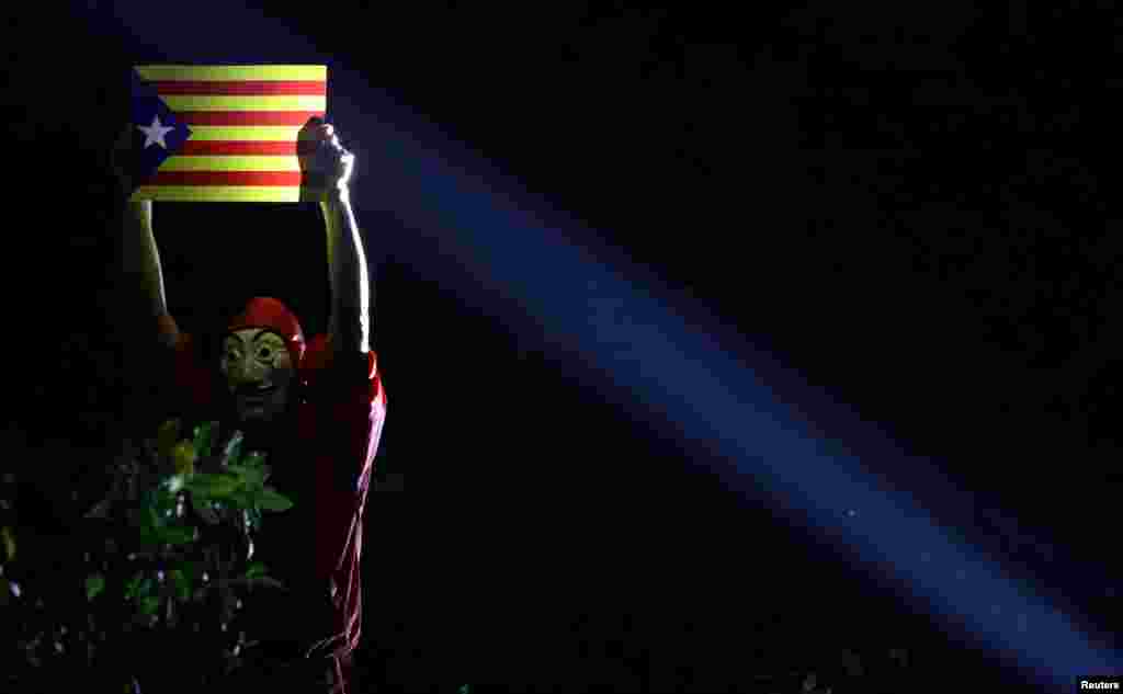 A pro-democracy demonstrator wearing a mask in Hong Kong holds an Estelada (Catalan separatist flag) during a protest in Hong Kong’s Chater Garden showing their solidarity with the Catalonian independence movement in Spain.
