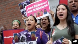 Protesters display placards and chant slogans, Aug. 14, 2019, while gathered outside federal court, in Boston. The demonstration was held to protest the Trump administration's campaign to end temporary protected status.
