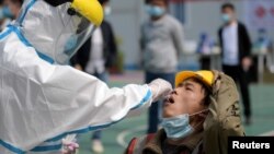 武漢一位醫護人員正在對一名建築工人採取進行核酸檢測的樣本。