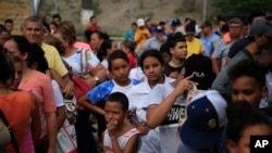 Migrantes de varios países latinoamericanos hacen fila para recibir alimentos de voluntarios estadounidenses al pie del puente que cruza a Brownsville, Texas, en Matamoros, México. Cientos esperan por meses en fila para solicitar asilo en EE.UU. Foto de junio 26 de 2019.