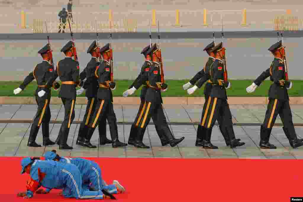 Workers clean a red carpet before a wreath-laying ceremony at the Monument to the People's Heroes in Tiananmen Square, marking the 70th anniversary of the founding of the People's Republic of China, in Beijing, China.