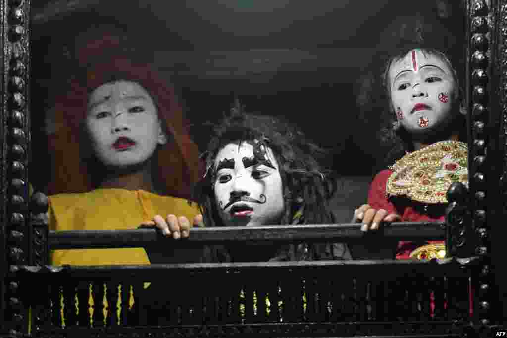 Young artists with painted face look out of a window before their performance at Basantapur Durbar Square on the second to last day of the 'Indra Jatra' Hindu festival in Kathmandu, Nepal, Sept. 16, 2019.