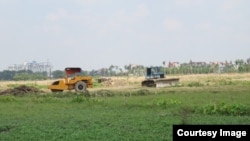 Ruộng đất của dân chưa đền bù xong nhưng các phương tiện thi công của chủ dự án vẫn ngang nhiên tiến hành san lấp. (Ảnh: Lê Anh Hùng)