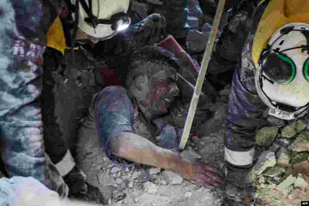 Members of the Syrian Civil Defense, also known as the White Helmets, rescue a survivor from the rubble of a collapsed building following a reported airstrike in the village of Balyun in Syria's northwestern Idlib province, Dec. 7, 2019.