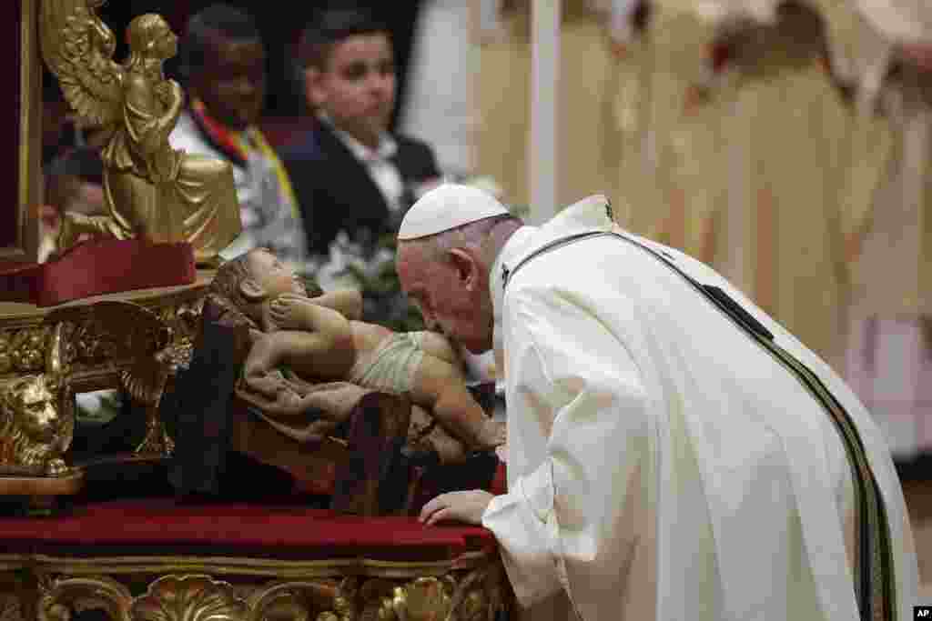 Pope Francis kisses a statue of Baby Jesus as he celebrates Christmas Eve Mass in St. Peter's Basilica at the Vatican, Dec. 24, 2019.