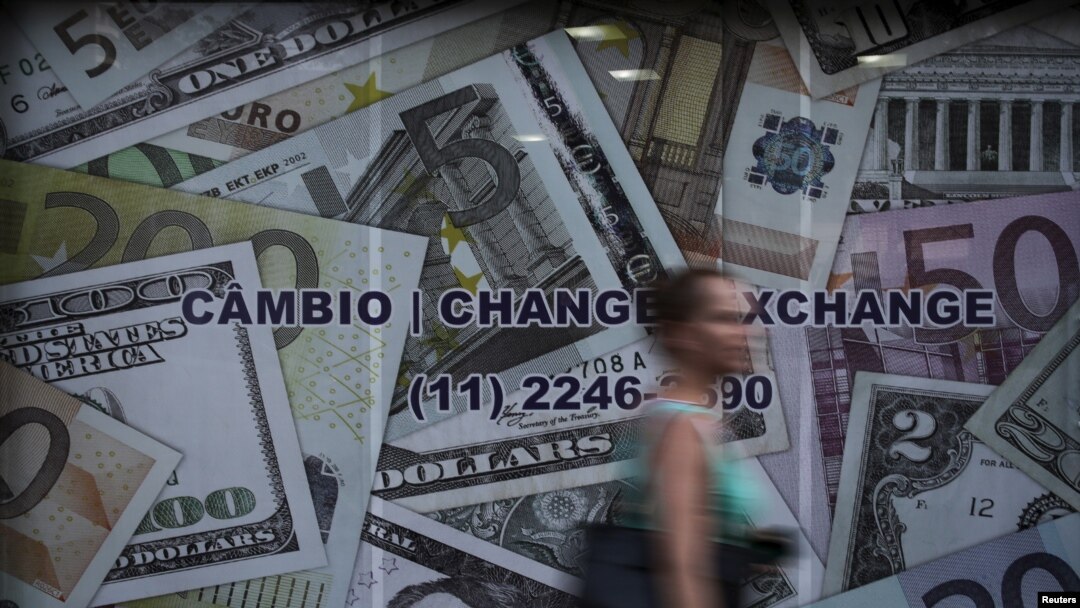 FILE - A woman walks past a currency exchange office in Sao Paulo, Brazil, Jan. 7, 2016.