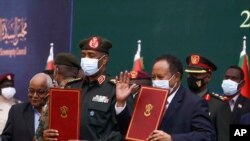 在這張由蘇丹過渡主權委員會提供的照片中，蘇丹高級將領布爾漢（中左）與哈姆杜克總理在一個儀式中手拿文件。
