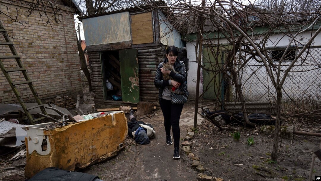 Una mujer camina con un gato entre los cadáveres de su esposo y un hermano en Bucha, Ucrania, el 4 de abril de 2022.