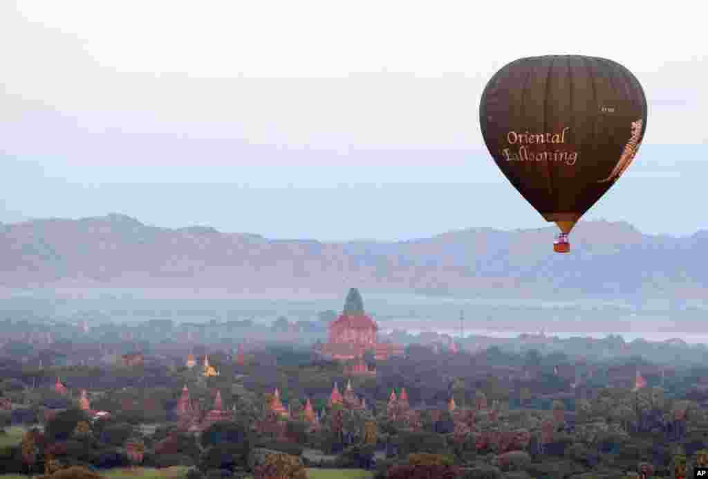 A hot air balloon flies over the Myanmar's ancient temples just before sunrise in old Bagan, Nyaung U district.