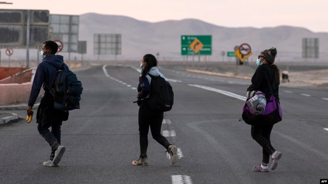 Venezolanos caminan por la carretera camino a Iquique, luego de cruzar desde Bolivia, en Colchane, Chile, el 18 de febrero de 2021.