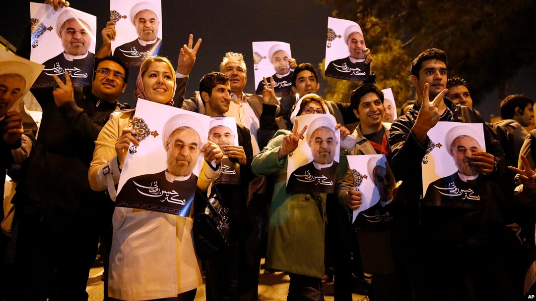 In this photo released by the Iranian Students News Agency, ISNA, Iranians hold posters of President Hassan Rouhani as they welcome Iranian nuclear negotiators upon their arrival from Geneva at the Mehrabad airport in Tehran, Nov. 24, 2013. 